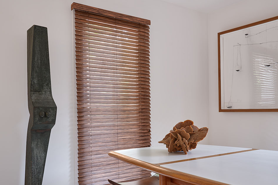 A modern dining room has a tall window with outside mount blinds showing how inside vs outside mount blinds are different