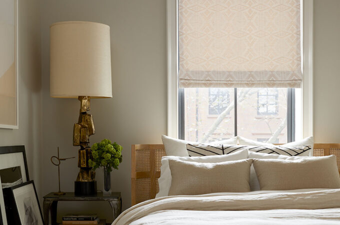 An inviting bedroom features a flat roman shade which is one of the types of window shades or types of shades for windows