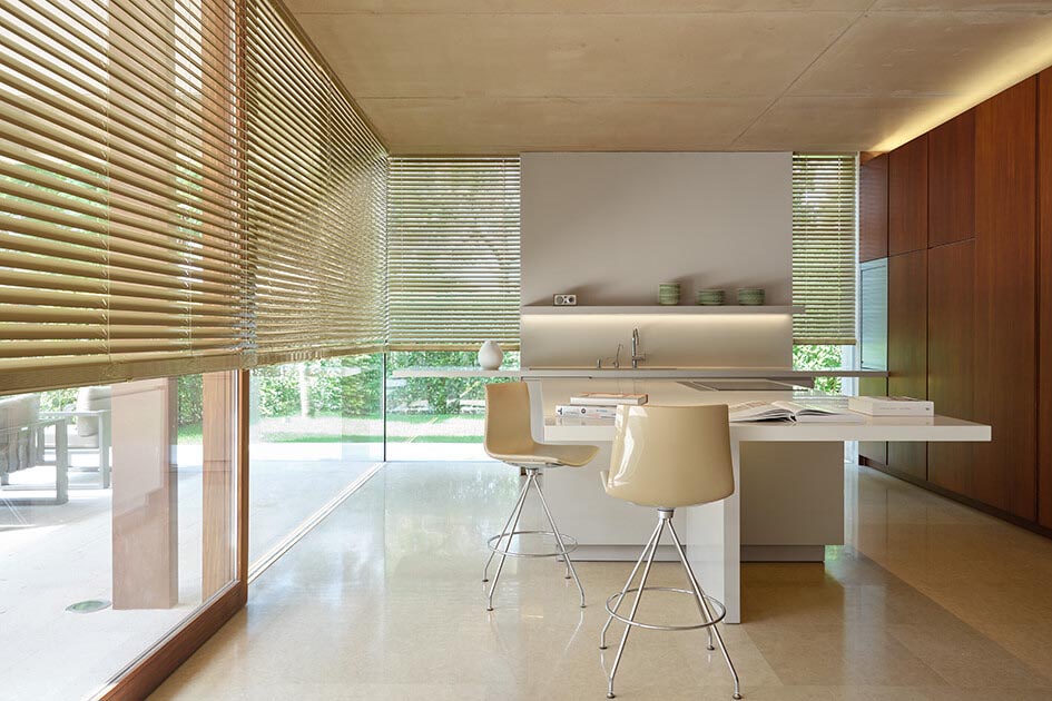 Large champagne-colored metal blinds are used as an alternative to shades for sliding doors in a kitchen