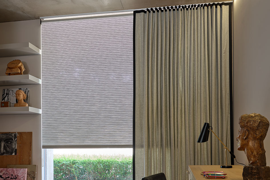 A modern office features a large floor to ceiling window with reverse roll roller shades in mesa verde mist and drapery