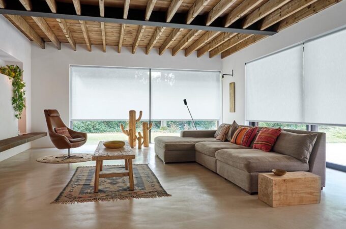 A bright living room has windows with reverse roll roller shades made of 3% solar shades in material thermo and color, cloud