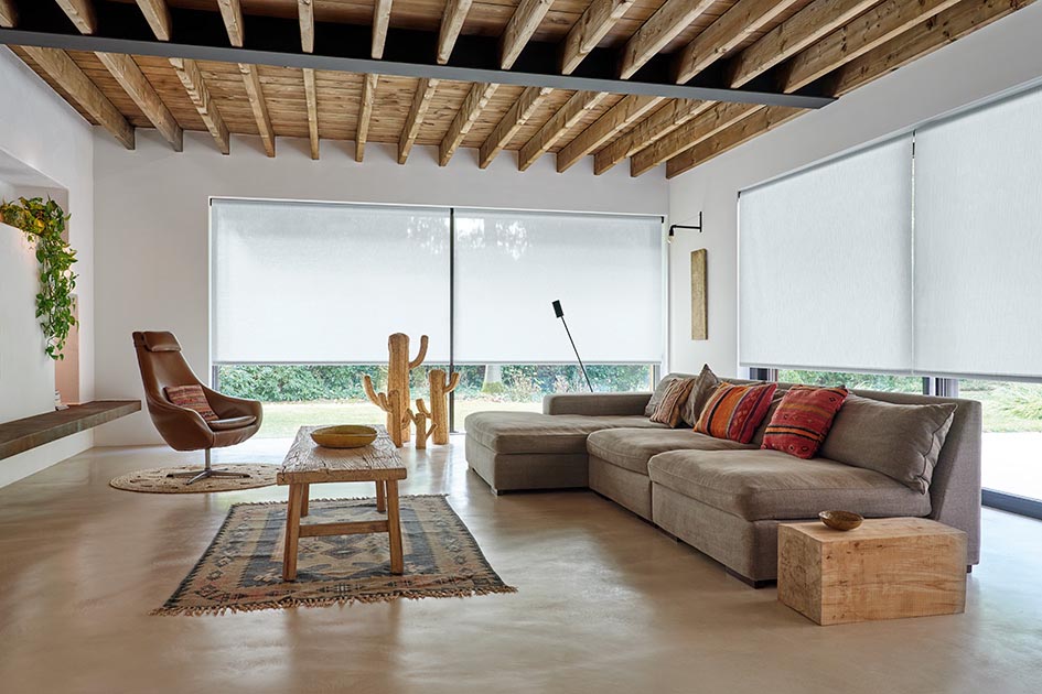 A bright living room has windows with reverse roll roller shades made of 3% solar shades in material thermo and color, cloud
