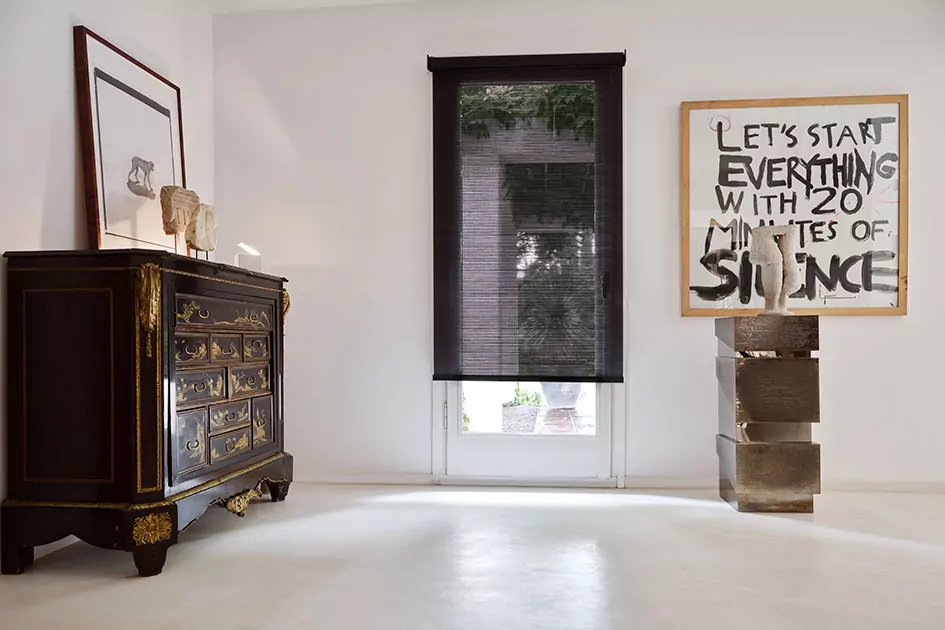 A hallway features a tall window with a semi-transparent solar shade which is one of the types of window shades