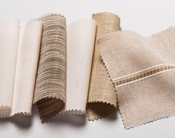 A variety of neutral colored fabric swatches laid out across a white background.