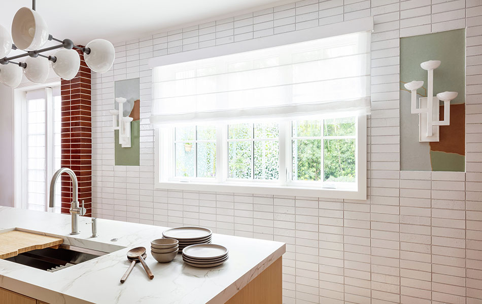 A contemporary kitchen with white brick walls has Aventura linen Roman Shades made of Lannister Sheer in White