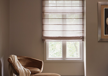 A reading nook has an Aventura Roman Shade made of Sheer Elegance in Cocoa for a delicate look that provides some privacy as decorative window coverings for soft natural light