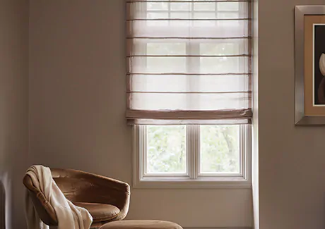 A reading nook has an Aventura Roman Shade made of Sheer Elegance in Cocoa for a delicate look that provides some privacy