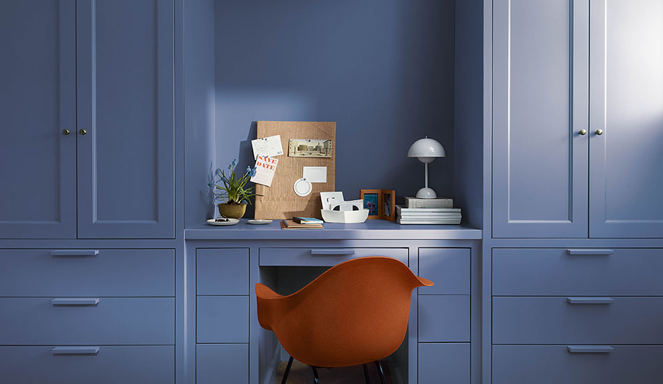 An office features a small desk and built-in cabinetry all painted in Benjamin Moore's color of the year 2024, Blue Nova