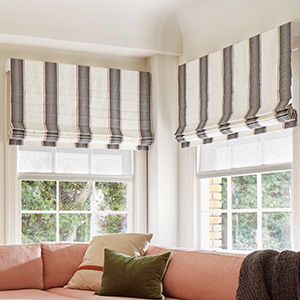 Cascade Roman Shades made of Nomad Stripe in Graphite add a bold striped pattern to a family room with a salmon couch