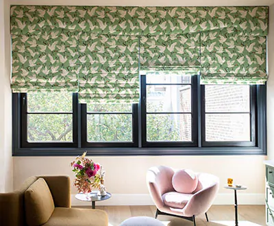 Four shades in light green and a pattern of decorative white cranes are pulled to varying levels on a series of windows