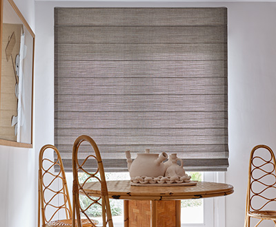 Woven shades made of Jackson in Sun offer a warm grey tone to complement to wood table in a mid-century modern dining room