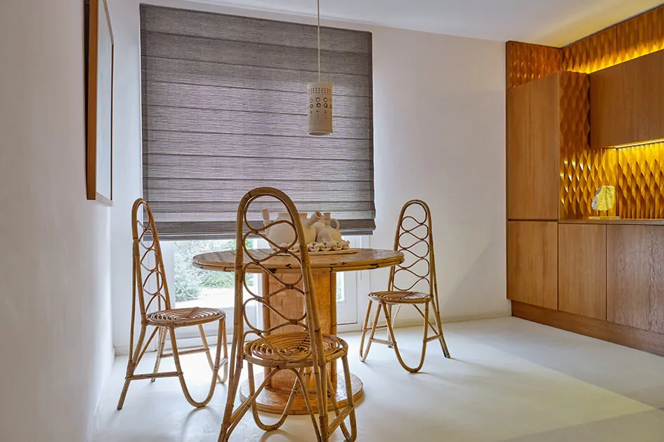 A dining room features grey cascade roman shades for sliding doors over the glass doors to the backyard