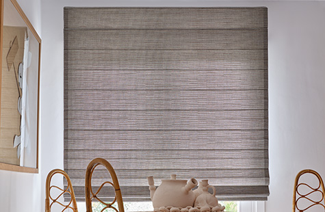 A mid-century modern dining room with a wood dining set features woven window shades made from Jackson material in Sun