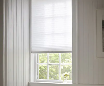 A small basement window features a Cellular Shade made of 3-4-inch Single Cell Light Filtering material in Lace