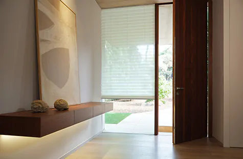 A Cellular Shade made of Napoli in Natural is used as window treatments for large windows in a mid-century modern entryway