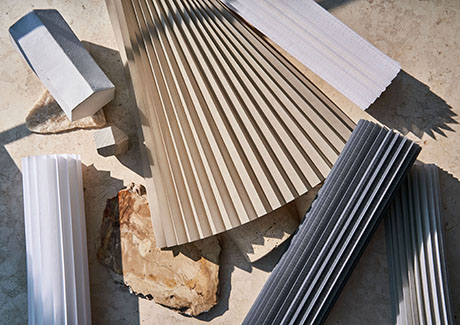 Cellular Shade swatches are folded decoratively so their pleats show on a rustic surface with stone accents
