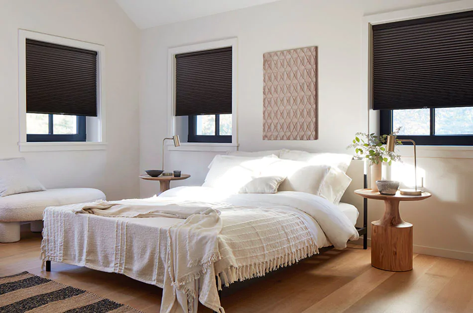 Modern window treatments in a bright bedroom are made with blackout cellular shades in a bold black color