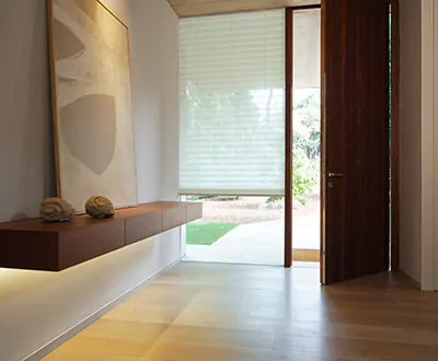 An entry way with minimalist, modern decor features Cellular Shades made of Napoli material in the color, Natural