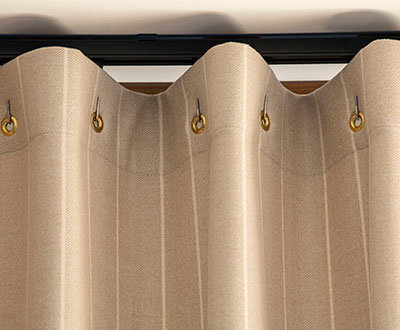 A close up of Cubicle Drapery made of Dashing Stripe in Palomino shows small grommets that create a gentle fabric wave
