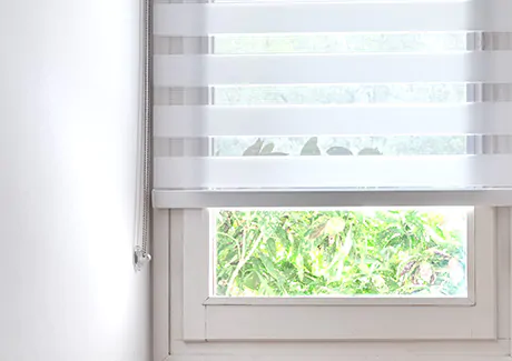A close up image shows a continuous loop control system on a set of Zebra Blinds made of Catalina in White