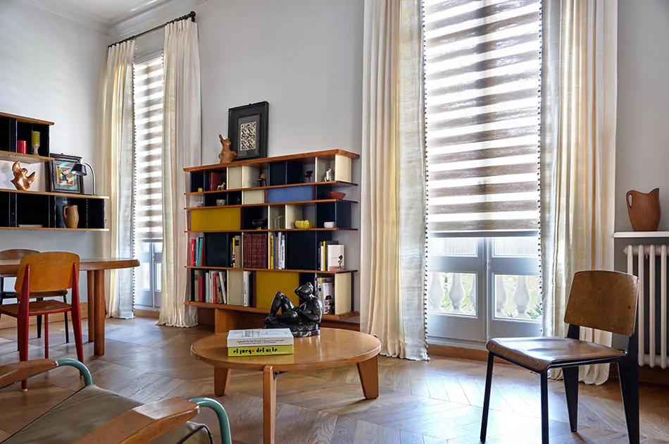 An inviting lounge with a mid-century modern aesthetic has Zebra Blinds made of Windansea in Canyon paired with silk Drapery