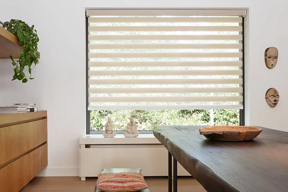 Mid century modern window treatments include beige double roller shades in a dining room with a rustic wood dining table