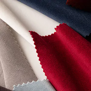 A collection of drapery swatches made of Posh Velvet are piled decoratively on a table and feature bold colors