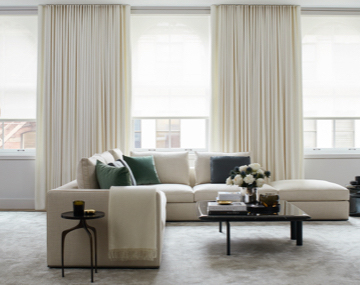 Large Windows featuring layered energy efficient window treatments in a living room with a large sectional couch with pillows