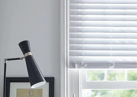 A set of Faux Wood Blinds in Blanc offer a modern linear look to show the difference between blinds vs shades