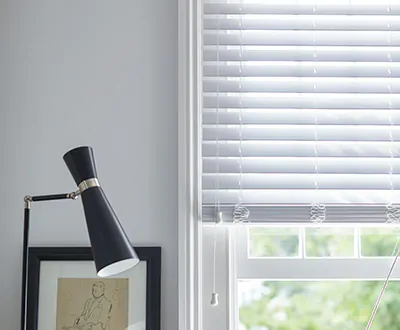 A small basement window features Faux Wood Blinds made of 2-inch Faux material in Blanc to match the white walls