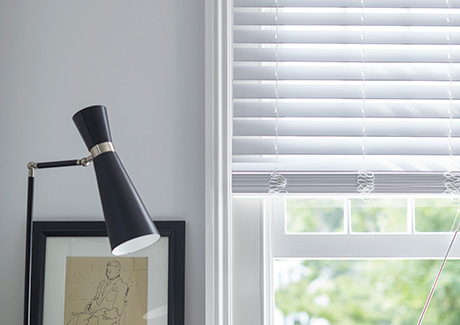 A set of Faux Wood Blinds in Blanc offer a modern linear look to show the difference between blinds vs shades