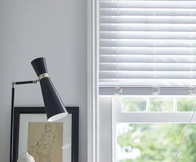 A small basement window features Faux Wood Blinds made of 2-inch Faux material in Blanc to match the white walls