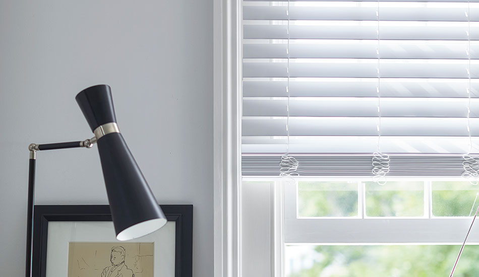 An office features colored window blinds made of 2-inch Faux wood in Blanc for a bright clean aesthetic