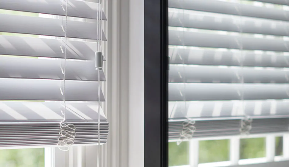 An image of faux wood blinds in Blanc being reflected in a mirror helps answer the question what is faux wood