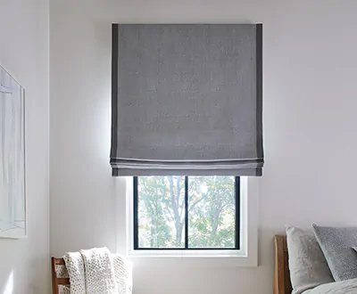 Roman shades for windows include a Flat Roman Shade made of Baldwin in Stone in a bedroom with cool gray-blue tones