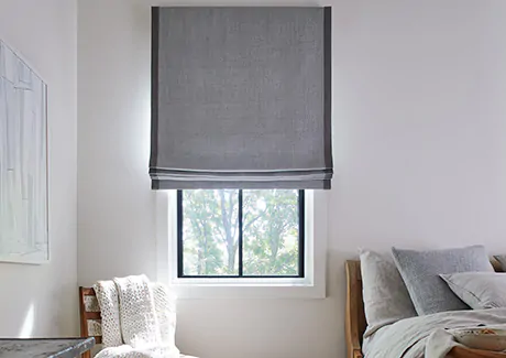 A bedroom features outside mount Roman Shades made of Baldwin in Stone which has a subtle miniature herringbone pattern