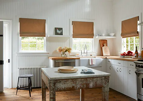 Farmhouse window treatments of Flat Roman Shades made of Cotton in Chino adorn the windows of a traditional farmhouse kitchen