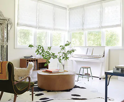 A mid-century modern sitting room has corner windows with Flat Roman Shades made of Feather Palm Embroidery in Vintage Lace