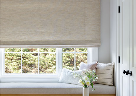 One of the window treatment trends 2024 is the use of natural fibers seen on these Flat Roman Shades in a bedroom