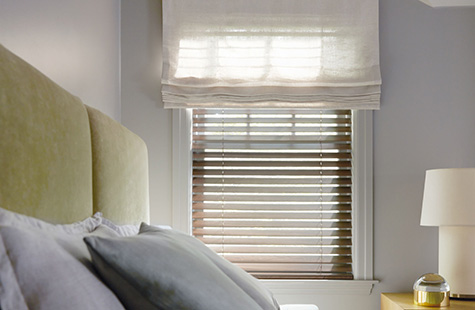 A Flat Roman Shade made of Linen Sheers in Oatmeal is layered with Wood Blinds made of 2-inch Laminated in Light Walnut