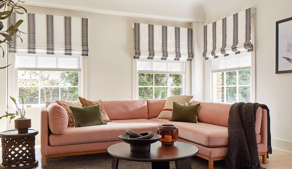 A family room features Flat Roman Shades made of Nomad Stripe in Graphite for a bold look in a casual space