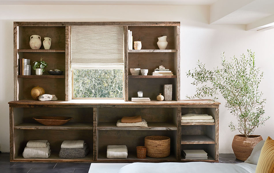 Flat linen Roman Shades made of Nate Berkus' Claude Stripe in Alabaster add a luxe look to a window between wood shelves