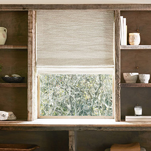 Pull down window shades in the Roman Shade style made of Claude Stripe, Alabaster, cover a window surrounded by wood shelving