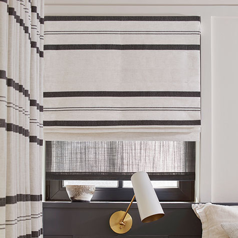 Window shades in a modern bedroom include Flat Roman Shade made of Shoreham Stripe in Jet for a striking look
