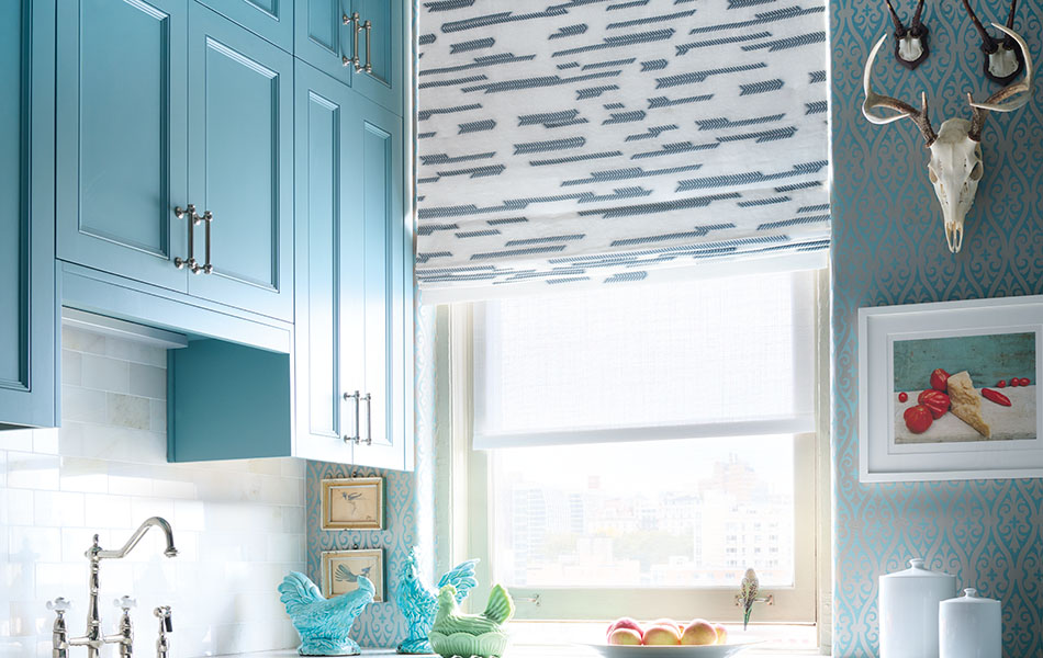 A Flat Roman Shade made of Sheila Bridges Archer in Lagoon adds a modern arrow design to a kitchen with turquoise cabinets