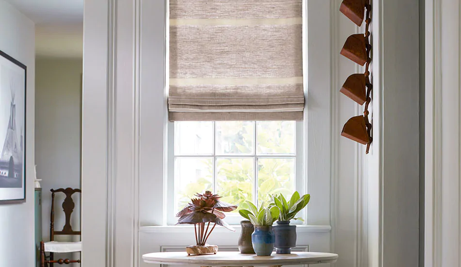 A hallway window has coastal window treatments of Flat Roman Shades made of Shoreham Stripe in Oatmeal