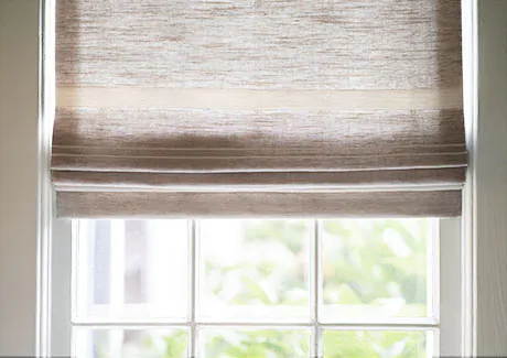 A close up of a type of coastal window treatments made of Flat Roman Shade in Shoreham Stripe, Oatmeal, shows a sandy color