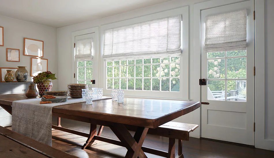 A dining room with a dark wood table has Flat Roman Shades made of Shoreline in Jade showing one type of roman shade styles