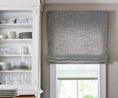 Flat linen Roman Shades made of Shoreline in Pewter add a rustic touch to a modern farmhouse kitchen with white cabinets