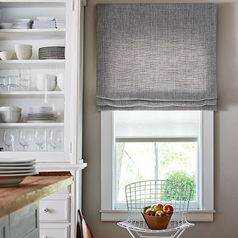 Roman Shades for kitchen windows made of Shoreline in Pewter cover a narrow window in a charming farmhouse kitchen